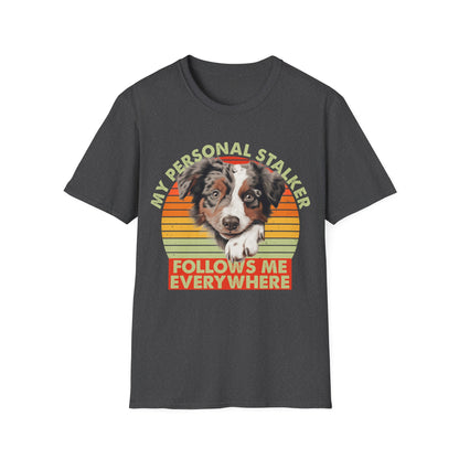 Dark heather unisex t-shirt Australian Shepherd with retro sunset and text that says 'My Personal Stalker Follows Me Everywhere', ideal for Aussie owners and dog lovers with Velcro dogs