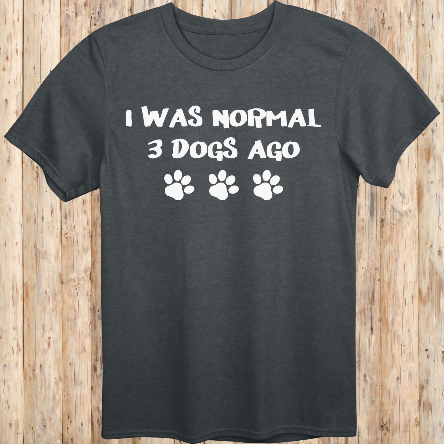 Dark heather unisex t-shirt with text that says 'I Was Normal 3 Dogs Ago', ideal for dog lovers and multiple pet owners