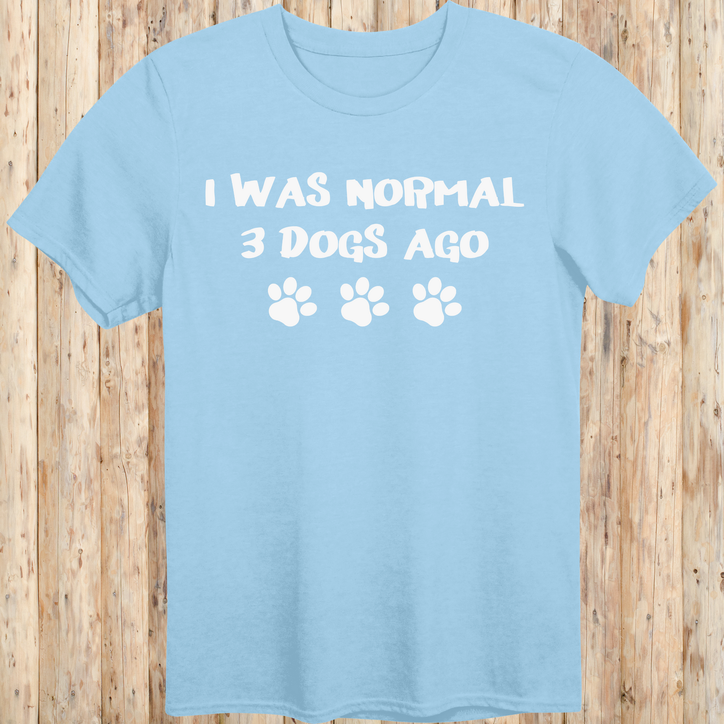 Light blue unisex t-shirt with text that says 'I Was Normal 3 Dogs Ago', ideal for dog lovers and multiple pet owners
