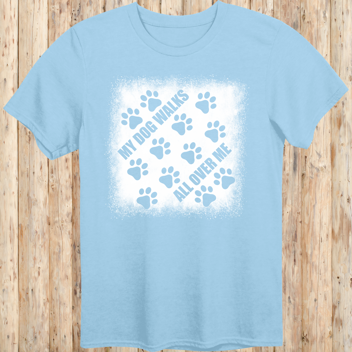 Light blue unisex t-shirt with paw prints and the phrase 'My Dog Walks All Over Me' printed on the front for men women adults and humans.