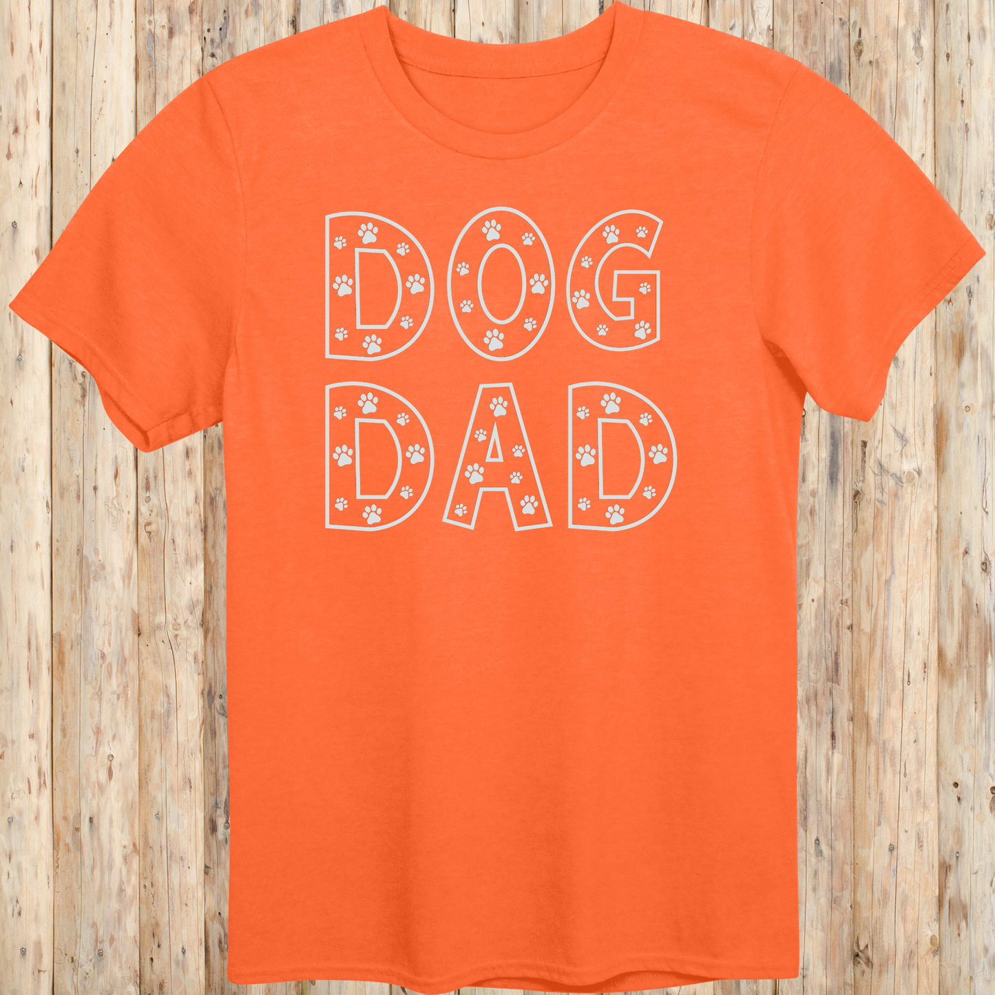 Orange unisex t-shirt with the words 'Dog Dad' in white text and small paw print accents, perfect for dog dads and pet owners