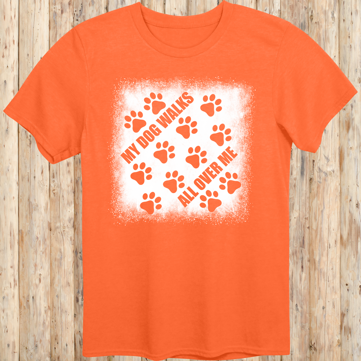Orange unisex t-shirt with paw prints and the phrase 'My Dog Walks All Over Me' printed on the front for men women adults and humans.