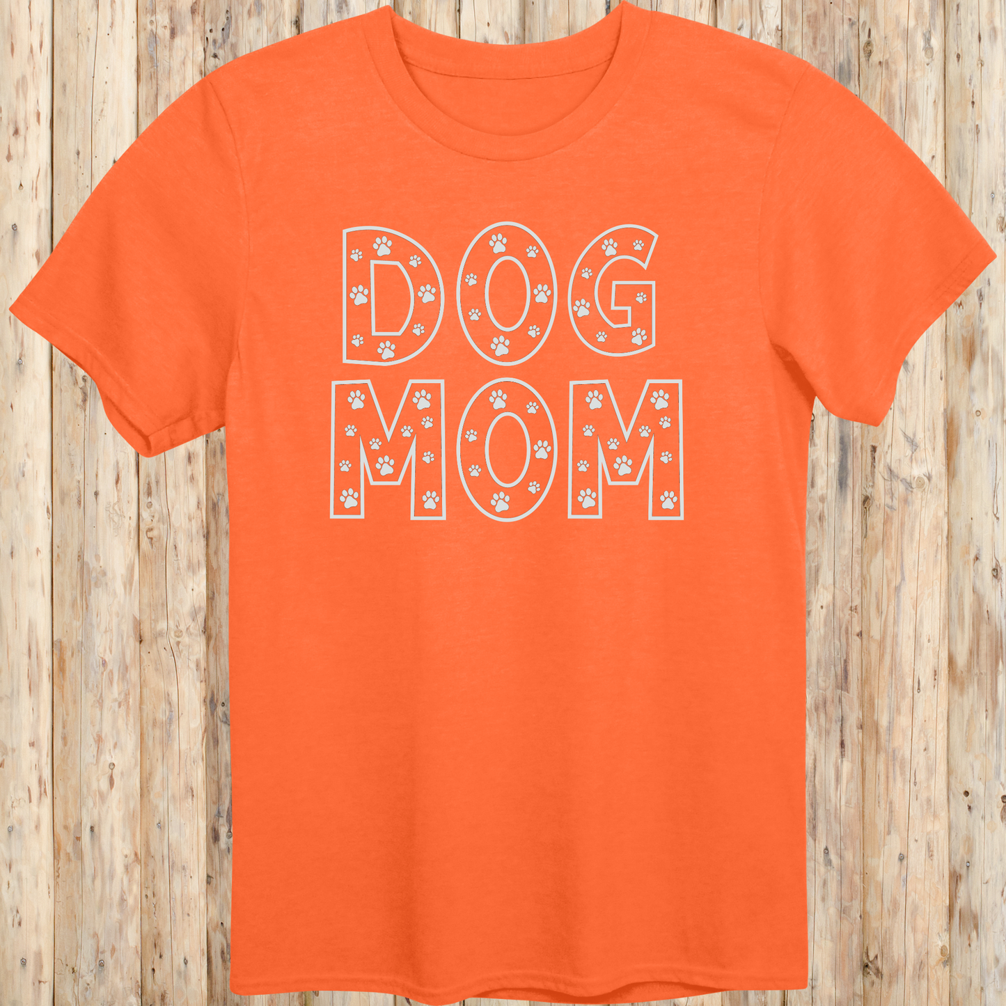 Orange unisex t-shirt with the words 'Dog Mom' in white text and small paw print accents, ideal for pet moms and dog lovers
