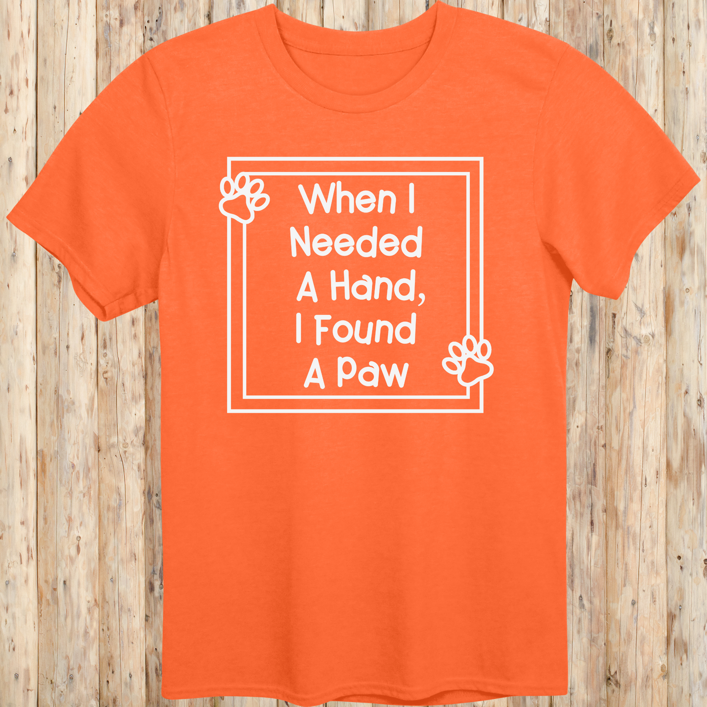 Orange unisex t-shirt with text that reads 'When I Needed a Hand I Found a Paw', ideal for dog lovers and rescue pet adopters